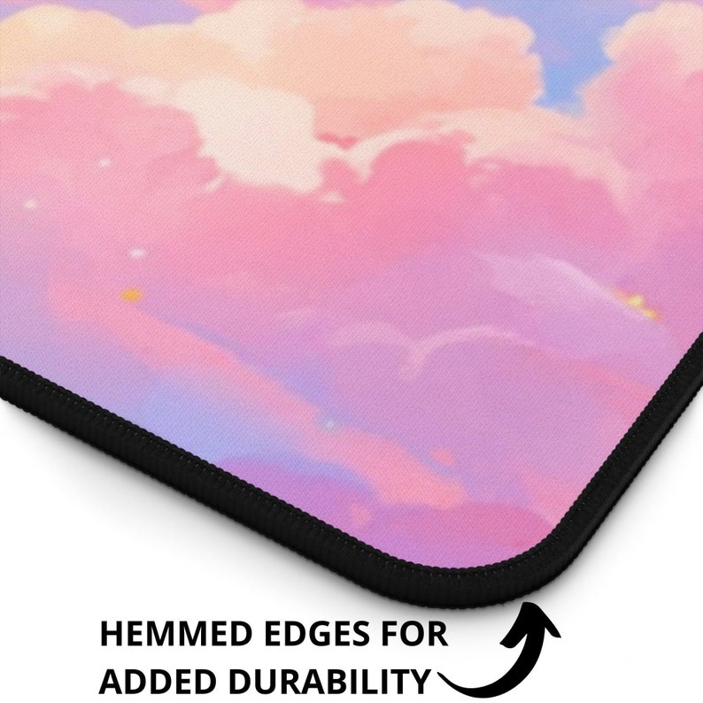 May include: A pink and purple mousepad with a cloud design. The edges are black and stitched for durability. "Hemmed edges for added durability" is written on the bottom of the image.