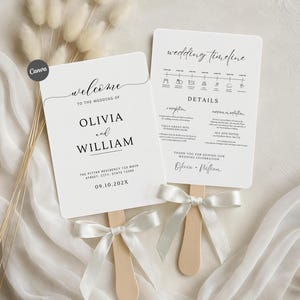 Pode incluir: Dois leques de casamento brancos com cabos de madeira e laços de fita brancos. Um leque diz "bem-vindo ao casamento de Olivia e William" com a data e o endereço. O outro leque exibe uma linha do tempo e detalhes do casamento.