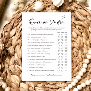 Puede incluir: Una tarjeta blanca de juego de boda con el texto "Over or Under" y una lista de preguntas. La tarjeta está rodeada por un fondo tejido de color canela y cuentas blancas. El juego está diseñado para ser jugado en una boda.