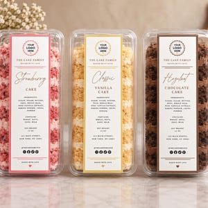 Puede incluir: Tres recipientes rectangulares de plástico transparente con pasteles de fresa, vainilla y chocolate. Cada etiqueta vertical muestra THE CAKE FAMILY, sabores, ingredientes, peso neto 340g e iconos de redes sociales.