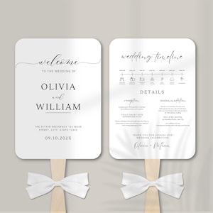 May include: Two white rectangular wedding programme fans with rounded corners, each attached to a wooden handle with a white ribbon bow. The left fan displays welcome text for Olivia and William, while the right fan shows a wedding timeline and details.