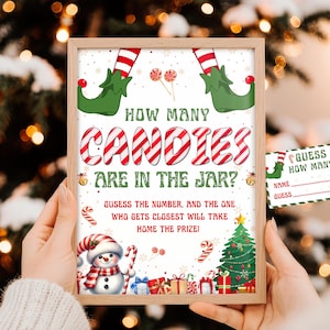 Könnte beinhalten: Ein gerahmtes Weihnachts-Partyspiel mit dem Text "How Many Candies Are in the Jar?" mit einem Schneemann, Weihnachtsbaum und Geschenken. Enthält eine passende "Guess How Many?" Karte. Das Spiel vor festlichem Hintergrund.