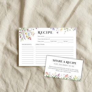 Op de afbeelding: Witte receptkaarten met bloemaccenten. De grotere kaart biedt ruimte voor ingrediënten en instructies. De kleinere kaart luidt "Deel een recept voor de bruid". Beide kaarten hebben een bloemenrand.