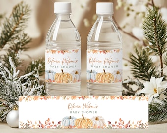 May include: Two clear water bottles with white caps and labels featuring watercolor pumpkins and fall foliage. The labels read "Olivia Wilson's BABY SHOWER." A matching banner is at the bottom. The bottles are surrounded by greenery and white flowers.