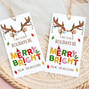 May include: Two white gift tags with a festive design. Each tag features reindeer antlers adorned with Christmas lights, the text "May Your Holidays Be Merry & Bright," and the name "The Willsons."