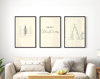 May include: Three framed art prints with black frames. The left print features line drawings of Christmas trees. The center print says "MERRY Christmas" in script. The right print shows a line drawing of a Christmas tree and a person. The prints are displayed above a beige sofa.