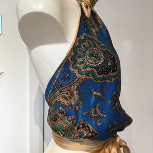 May include: A blue and gold halter top with a paisley print. The top is tied at the neck and waist with a gold ribbon.