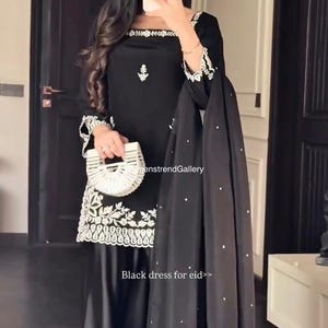 May include: Black dress with white floral embroidery on the neckline, sleeves, and hem. The dress has long sleeves and is paired with matching wide-leg trousers and a black scarf with white dots. The text "Black dress for eid>>" is visible.