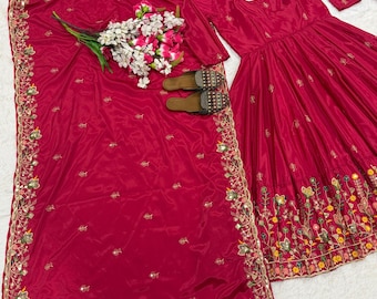 May include: A vibrant fuchsia-colored ensemble featuring a long-sleeved dress with floral embroidery, a matching shawl, and embellished sandals. A bouquet of white and pink flowers rests on the shawl.