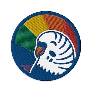 May include: Embroidered patch featuring a rainbow background and a white bird with a blue beak and blue and white stripes. The bird is facing left and is partially obscured by the rainbow.