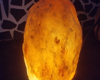 Könnte beinhalten: Eine große, orangefarbene Himalaya-Salzlampe mit einem warmen, leuchtenden Licht.