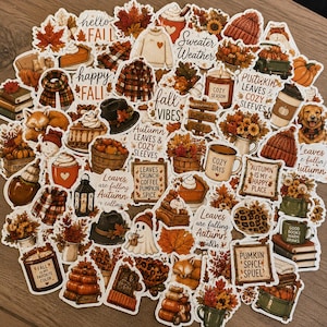 May include: A collection of autumn-themed stickers featuring pumpkins, fall foliage, cozy sweaters, warm beverages, and seasonal text like Sweater Weather, Fall Vibes, and Pumpkin Spice. The designs include foxes, hats, and books in warm orange tones.