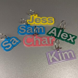 Glänzendes Finish Großverkauf Sammelbestellung Glitter Name Schlüsselanhänger und Taschenanhänger mit Farboffset