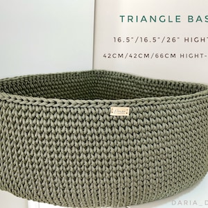 May include: A green crocheted triangle basket with a label that says "Daria Decor". The basket is 16.5 inches wide, 16.5 inches long, and 26 inches high. It is 10 inches tall.