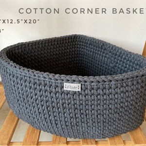 May include: A gray cotton corner basket, approximately 12.5" x 12.5" x 20" with an 8" height. The basket has a triangular shape, ideal for corners, and is made of a thick, knitted material. The text "COTTON CORNER BASKET" is visible.