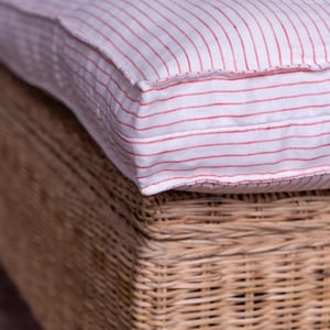 May include: A white and red striped cushion with a woven wicker base.