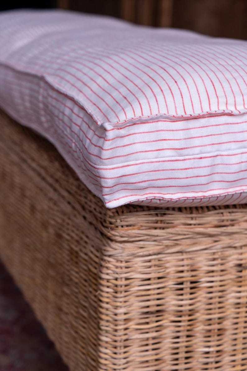 May include: A white and red striped cushion with a woven wicker base.