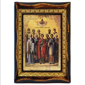 May include: A framed religious icon featuring a detailed painting of several figures in robes, with a gold background and ornate frame. The frame has a dark brown outer edge and a gold inner border with leaf designs. The text "ΟΙ ΑΓΙΟΙ ΔΩΔΕΚΑ ΑΝΑΡΓΥΡΟΙ" is visible.