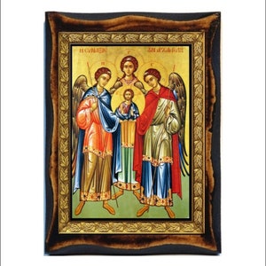 Peut inclure: Une icône encadrée représentant trois anges avec des halos et des ailes dorés. Les anges se tiennent devant une petite figure de Jésus-Christ. L'icône est peinte dans un style traditionnel avec des couleurs vives et des détails complexes. Le cadre est en bois foncé avec une bordure dorée.