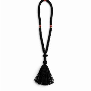 Può includere: Corda di preghiera nera annodata con nappa e ciondolo a forma di croce. La corda presenta perline rosse e dettagli dorati. Questo articolo religioso è progettato per la preghiera e la meditazione.