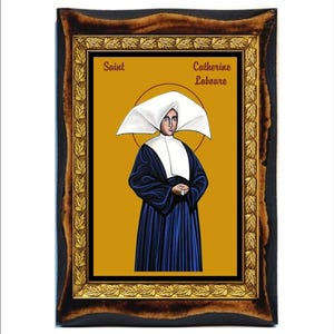 May include: A framed icon of Saint Catherine Labouré, a Catholic saint. The icon depicts her in a white habit with a blue robe, holding a rosary in her hands. The background is a golden yellow colour. The frame is dark brown with gold accents.