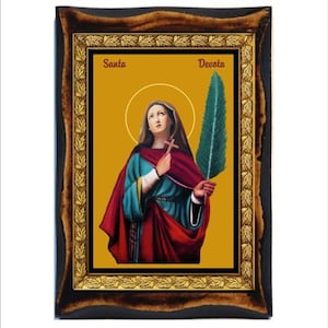 May include: A framed religious icon depicting a woman holding a cross and a palm branch. The icon has a gold background and is framed in a dark wood frame with gold accents. The text "Santa Devota" is written at the top of the icon.