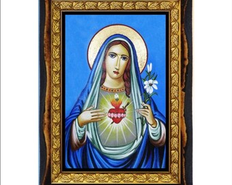May include: A framed religious icon featuring a woman in blue robes with a gold halo. The image depicts a heart with a flame and a sword, and the woman holds a white lily. The frame is dark brown with a gold inner border.