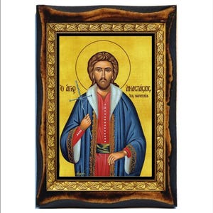 May include: A framed icon of a religious figure with a blue robe and a gold background. The icon is titled "Ο άγιος Αναστάσιος εκ, Ναυπλίας".