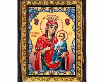 May include: A framed religious icon featuring a woman in a red robe and crown holding a child in a blue robe. The icon has gold accents and is set in a dark wood frame with a decorative border. The background is yellow with text.