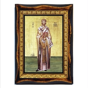 Könnte beinhalten: Eine Ikone einer religiösen Figur in einem goldfarbenen Rahmen. Die Figur trägt ein goldfarbenes Gewand und hält ein Buch. Der Rahmen ist dunkelbraun mit einem goldenen Innenrand und einem dekorativen Blattmuster.