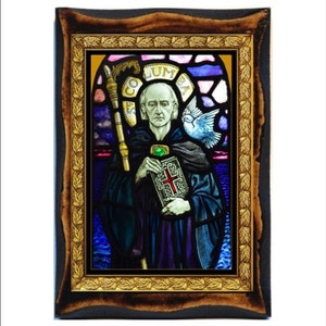 May include: A stained glass window depicting Saint Columba, a Christian missionary and abbot, holding a book and a staff. The window is framed in a dark wood frame with a gold leaf border.