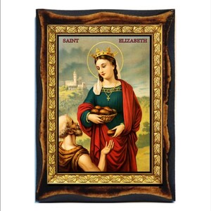 Puede incluir: Un icono religioso enmarcado que representa a Santa Isabel, una mujer con una corona y una túnica roja, sosteniendo una cesta de pan. Un hombre se arrodilla ante ella, extendiendo la mano. El icono tiene un marco dorado con un diseño de hojas.