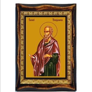 May include: A framed icon of Saint Benjamin. The icon is painted in a traditional style with gold accents and a yellow background. The saint is depicted with a white beard and a red and green robe.