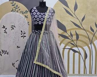 Puede incluir: Un lehenga bordado en blanco y negro con un choli bordado en blanco y negro a juego. El lehenga tiene un dupatta de red con un borde dorado.