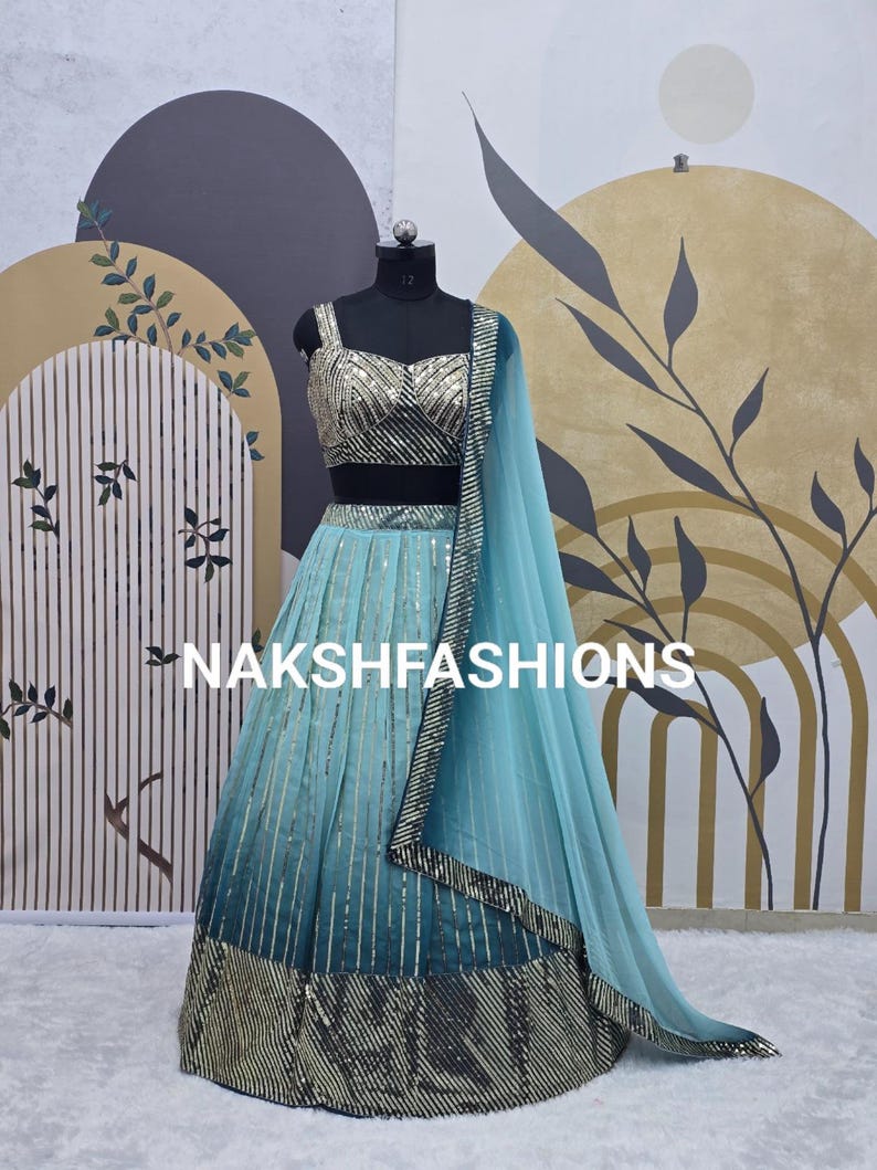 Op de afbeelding: Een lichtblauwe en turquoise lehenga met zilveren pailletten en een bijpassend topje. De outfit is op een mannequin en heeft een doorschijnende dupatta.