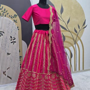 Pode incluir: Um lehenga bordado em rosa e dourado com um top curto rosa combinando. O lehenga tem uma saia em camadas com bordados dourados e lantejoulas. O dupatta &eacute; um tecido rosa transparente com bordados dourados.