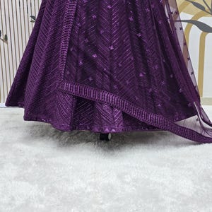 Puede incluir: Una falda de lentejuelas morada con una superposici&oacute;n transparente a juego. La falda tiene un patr&oacute;n de chevron y un borde decorativo.