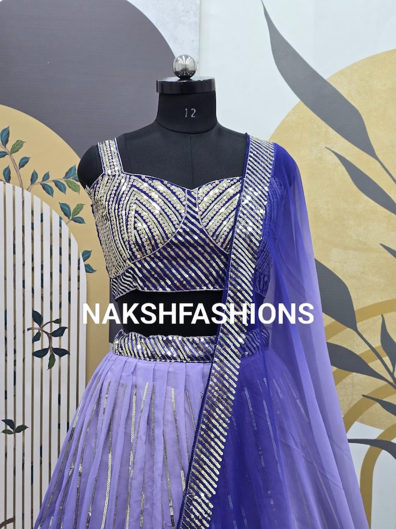 Op de afbeelding: Een paarse en blauwe sequined lehenga met een bijpassend topje. De outfit is versierd met zilveren sequins en heeft een doorschijnende blauwe dupatta.