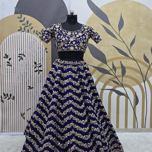 May include: A navy blue and gold embroidered skirt and matching crop top. The skirt has a wavy pattern and the top has a square neckline.