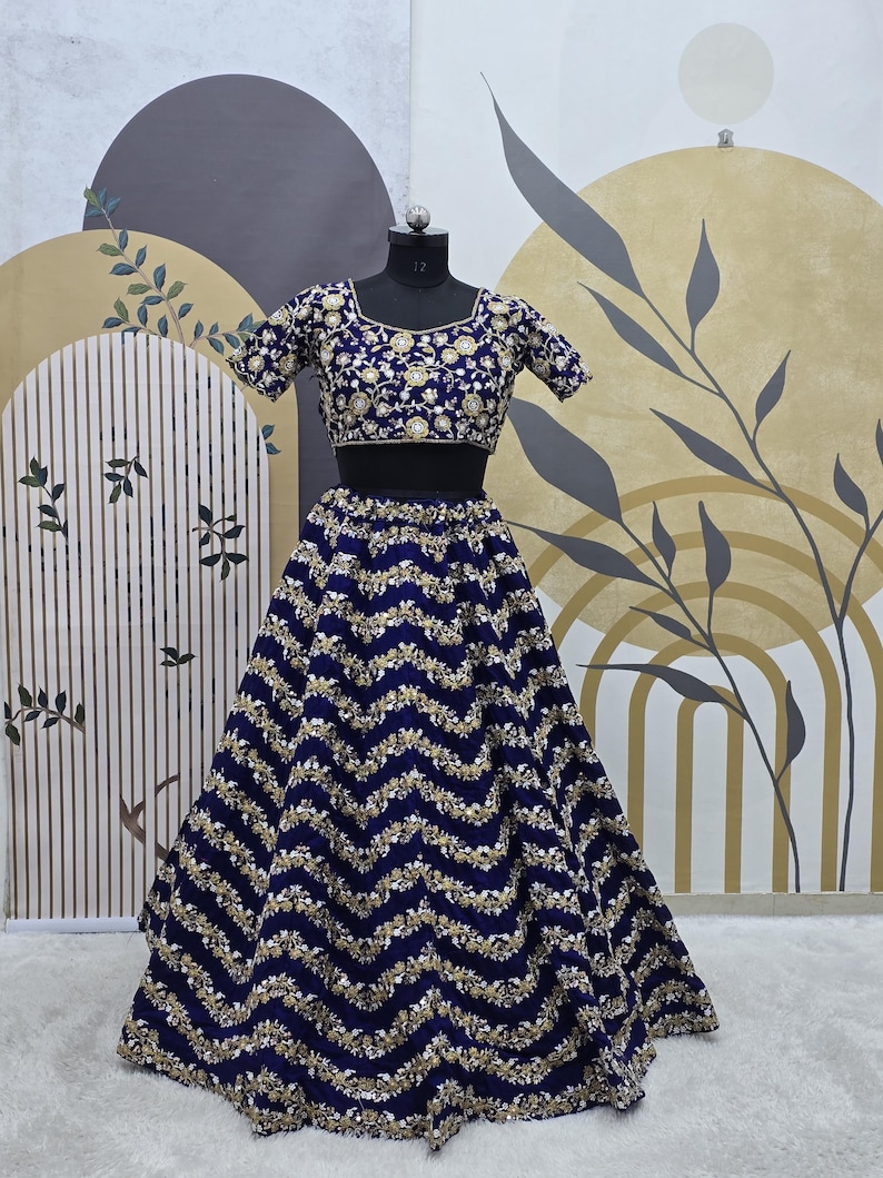 May include: A navy blue and gold embroidered skirt and matching crop top. The skirt has a wavy pattern and the top has a square neckline.