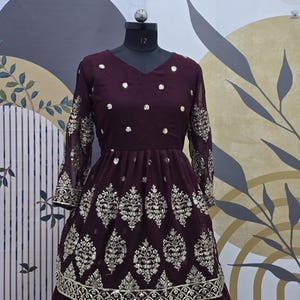 May include: A maroon long-sleeved dress with a V-neckline and a layered skirt. The dress is decorated with silver sequins and embroidery in a floral pattern.