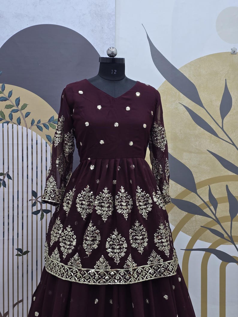 May include: A maroon long-sleeved dress with a V-neckline and a layered skirt. The dress is decorated with silver sequins and embroidery in a floral pattern.