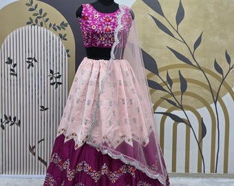 Può includere: Un lehenga ricamato rosa e viola con un choli senza maniche abbinato. Il lehenga ha uno strato superiore rosa con ricami argentati e uno strato inferiore viola con ricami floreali. Il choli è senza maniche e ha una base rosa con ricami floreali. Il lehenga è abbinato a un dupatta rosa trasparente.