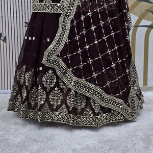 May include: A maroon skirt with silver embroidery and sequins. The skirt has a net overlay with a geometric pattern.