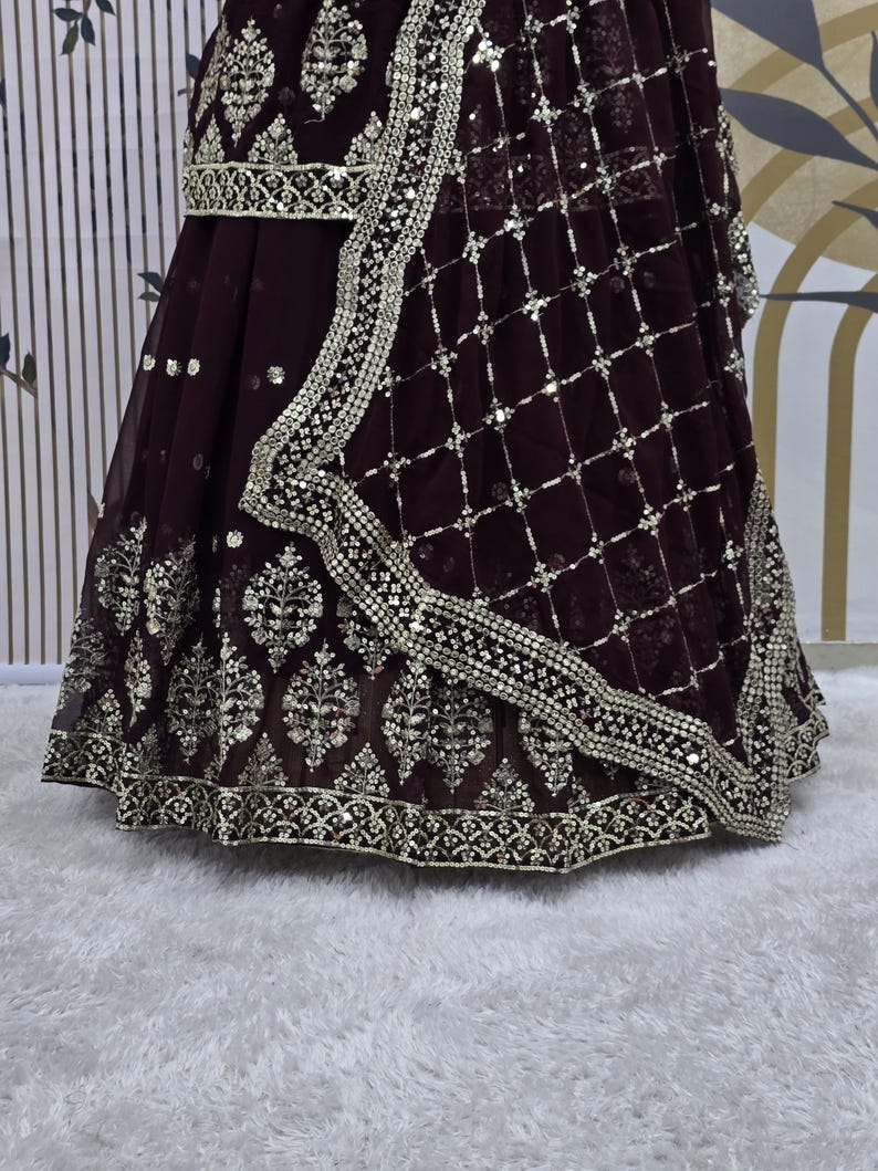 May include: A maroon skirt with silver embroidery and sequins. The skirt has a net overlay with a geometric pattern.
