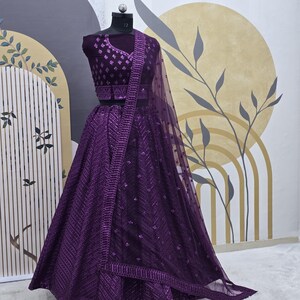 Puede incluir: Un lehenga bordado de color morado con un choli a juego. La falda est&aacute; hecha de una tela transparente con lentejuelas y un dobladillo festoneado. El choli tiene un escote en V y tambi&eacute;n est&aacute; adornado con lentejuelas.