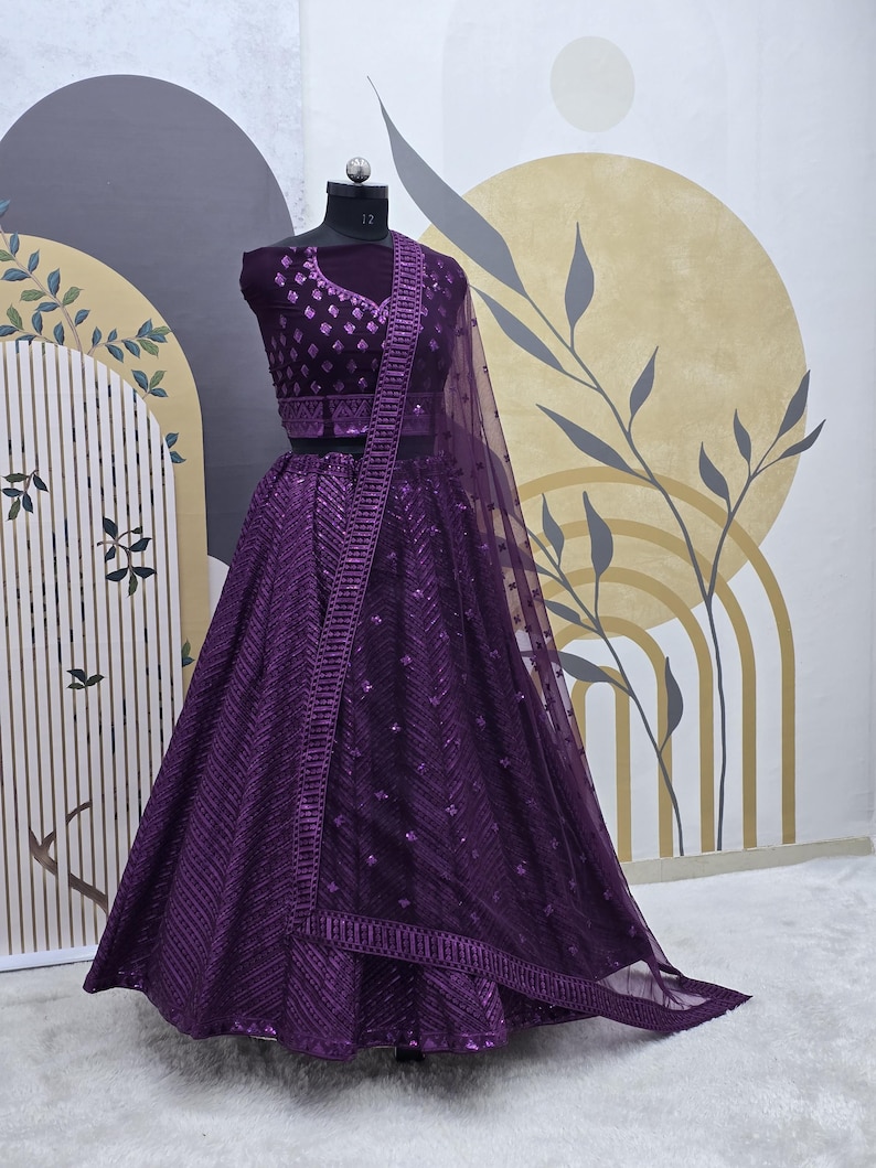 Puede incluir: Un lehenga bordado de color morado con un choli a juego. La falda est&aacute; hecha de una tela transparente con lentejuelas y un dobladillo festoneado. El choli tiene un escote en V y tambi&eacute;n est&aacute; adornado con lentejuelas.