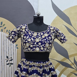 May include: A blue and gold embroidered crop top and skirt set. The top has short sleeves and a round neckline. The skirt is full length and has a gathered waist.