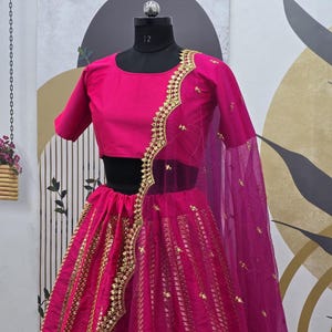 Pode incluir: Um lehenga magenta com bordados dourados e lantejoulas. A saia &eacute; feita de um tecido transparente com um dupatta magenta combinando.
