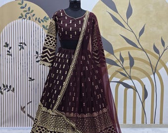 Puede incluir: Un lehenga bordado en color marrón y dorado con un choli a juego. El lehenga tiene una falda acampanada con un borde dorado y un dupatta de red.